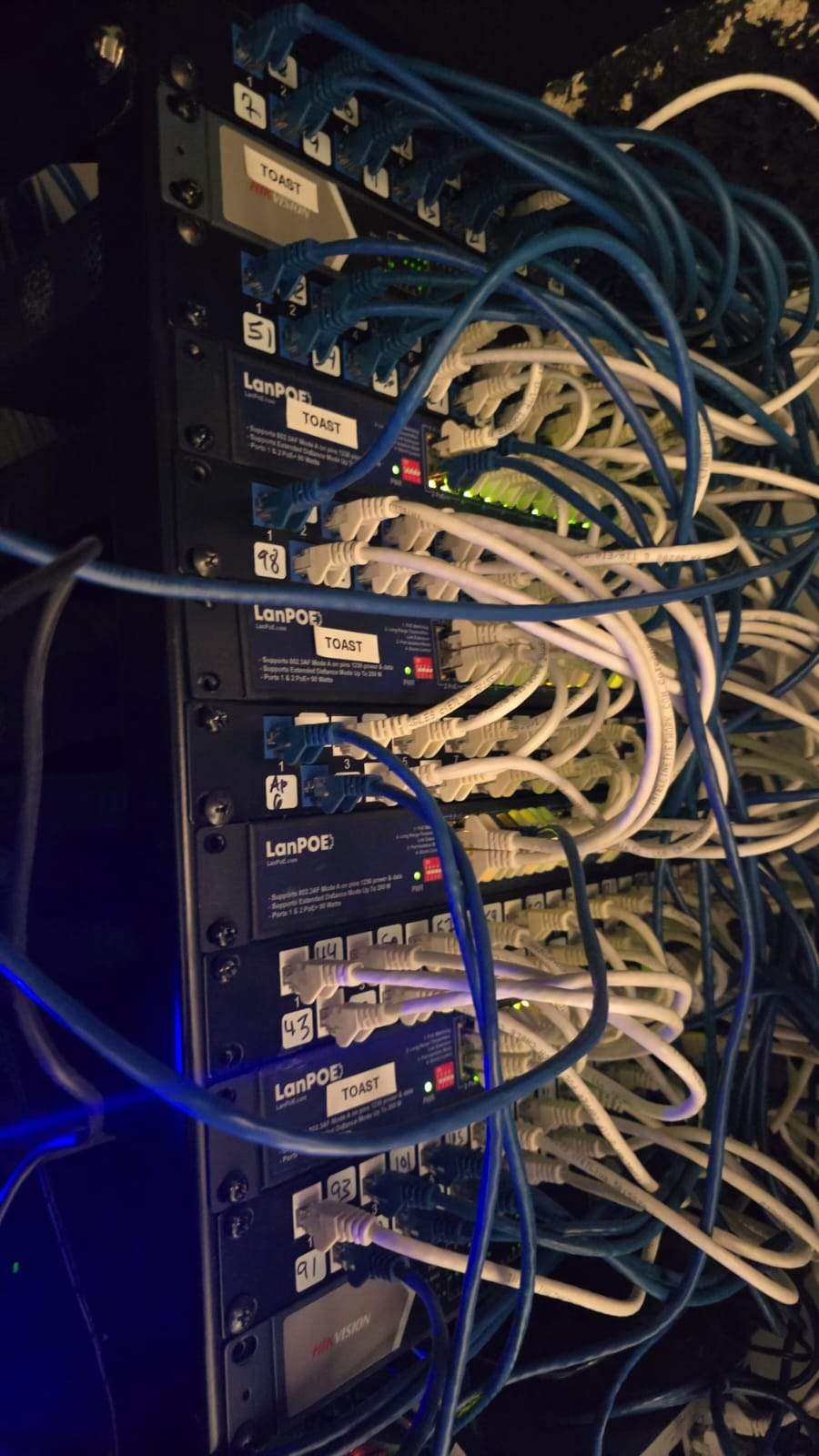 Stack of unmanaged switches with no labeling, cables tangled together