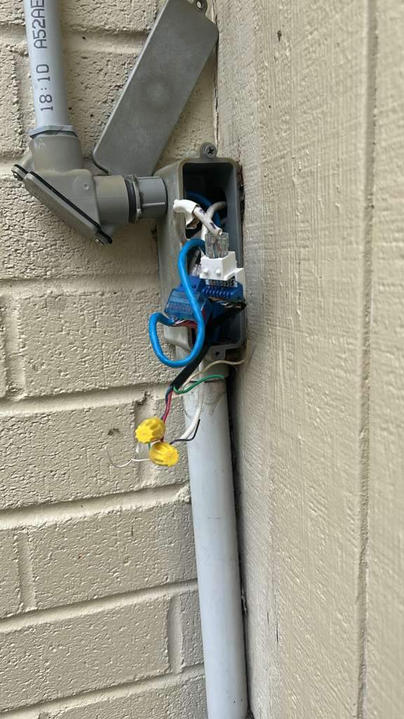 Exposed, deteriorating wiring splice in an outdoor junction box before cleanup