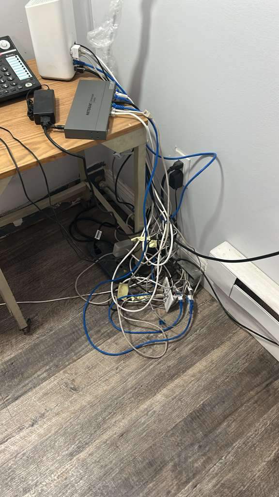Tangled network cabling piled on the office floor before cleanup